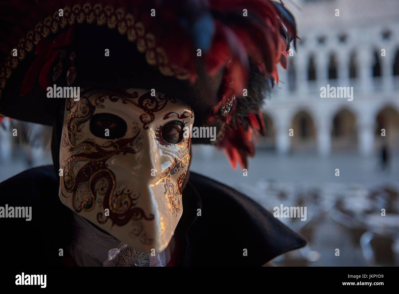 Celebrating Carnival in Venice 2017 in a Bauta mask with a hat garnished with red feathers. Stock Photo