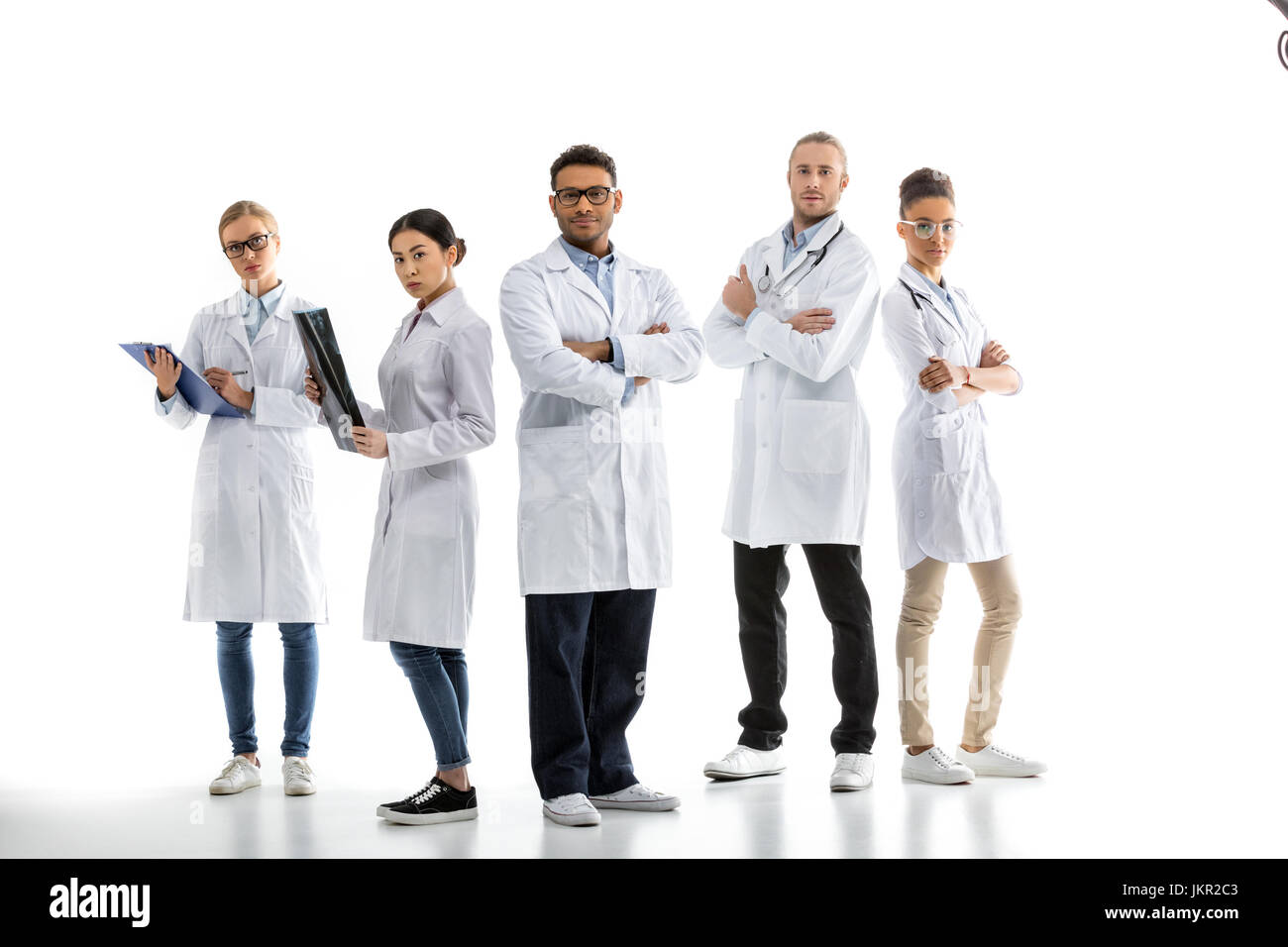 Group of young confident professional doctors in white coats standing