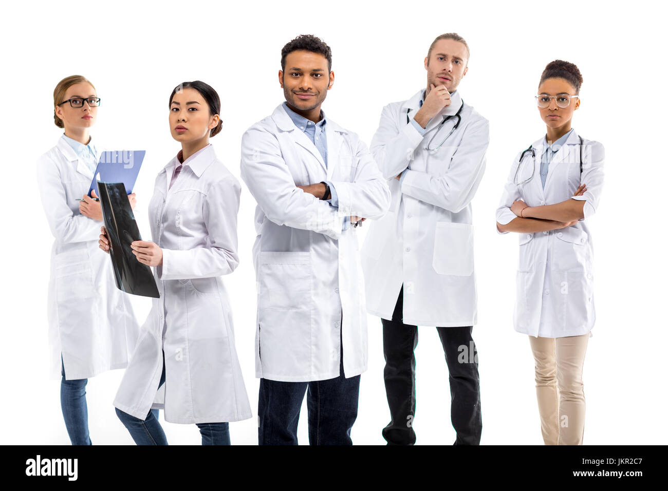 Group of young confident professional doctors in white coats standing isolated on white Stock
