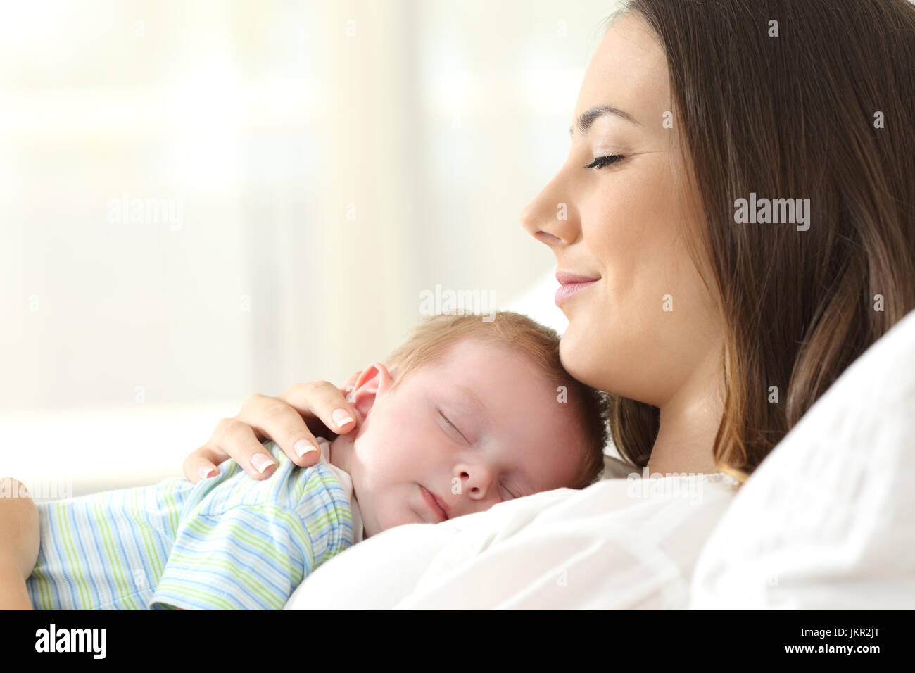 Profile of a happy mother sleeping with her baby on a bed at home Stock Photo