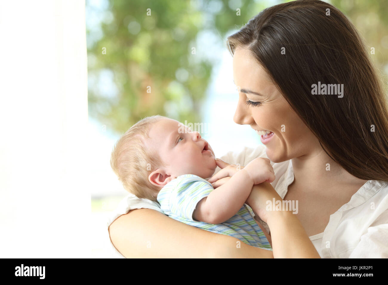 Mother holding and playing with her baby at home Stock Photo