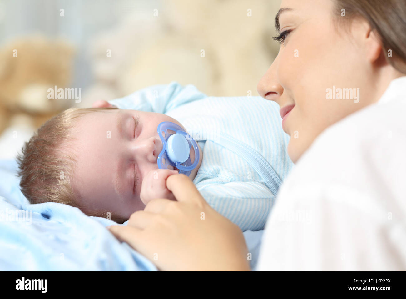 Close up of a mother watching her baby sleeping on a bed Stock Photo