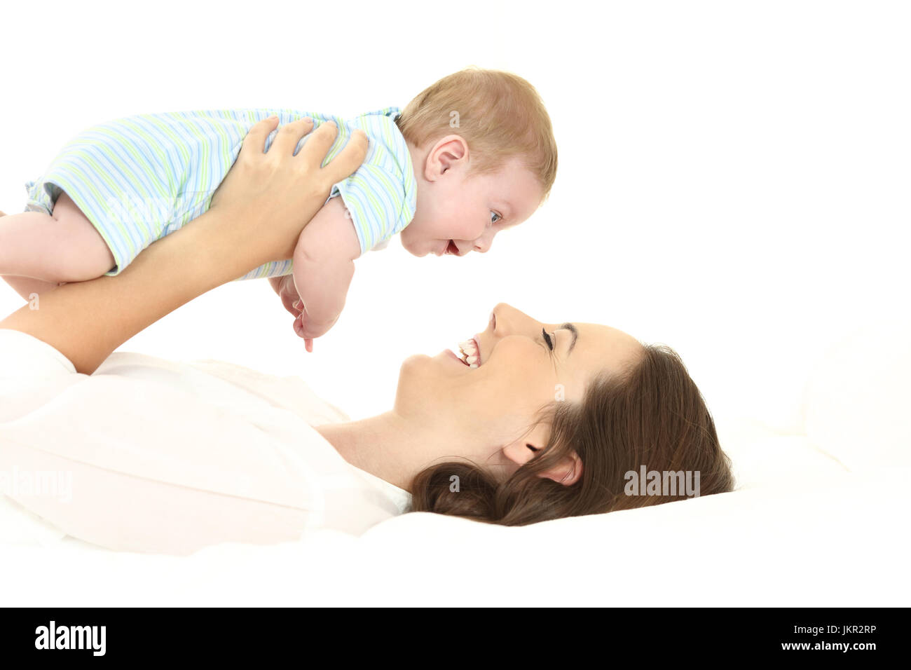 Side view portrait of a mother raising her baby lying on a bed Stock Photo