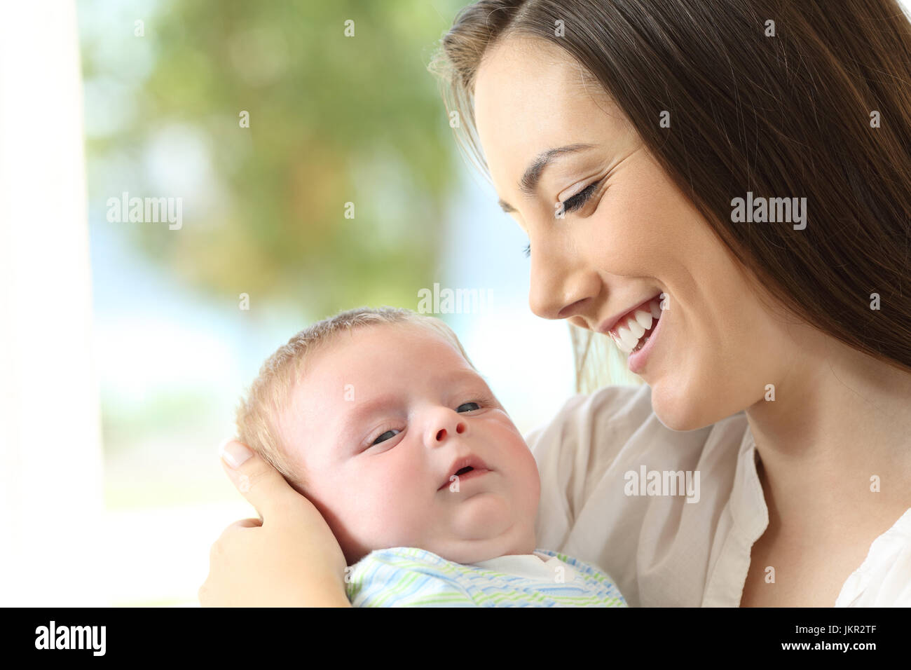 Portrait of a proud mother holding her baby and looking at him Stock Photo