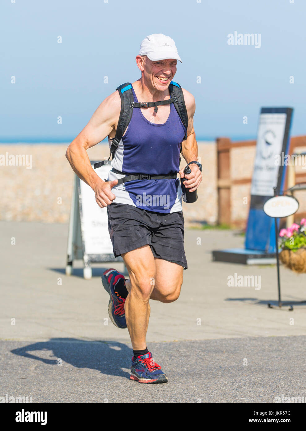 Man jogging and smiling on a seafront promenade. Stock Photo