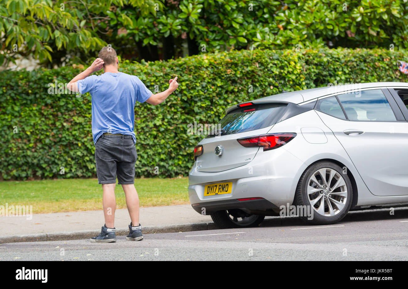 Man helping someone park their car by standing behind giving directions. Stock Photo