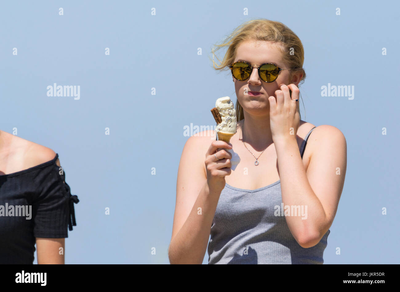 Young woman eating an ice cream cone on a hot day in Summer. Stock Photo
