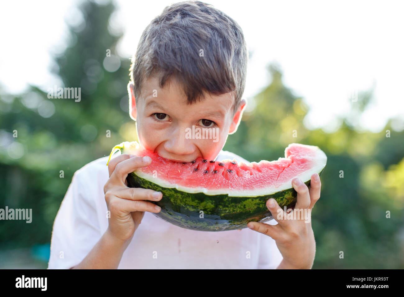 Little kid bite into watermelon outdoor Stock Photo