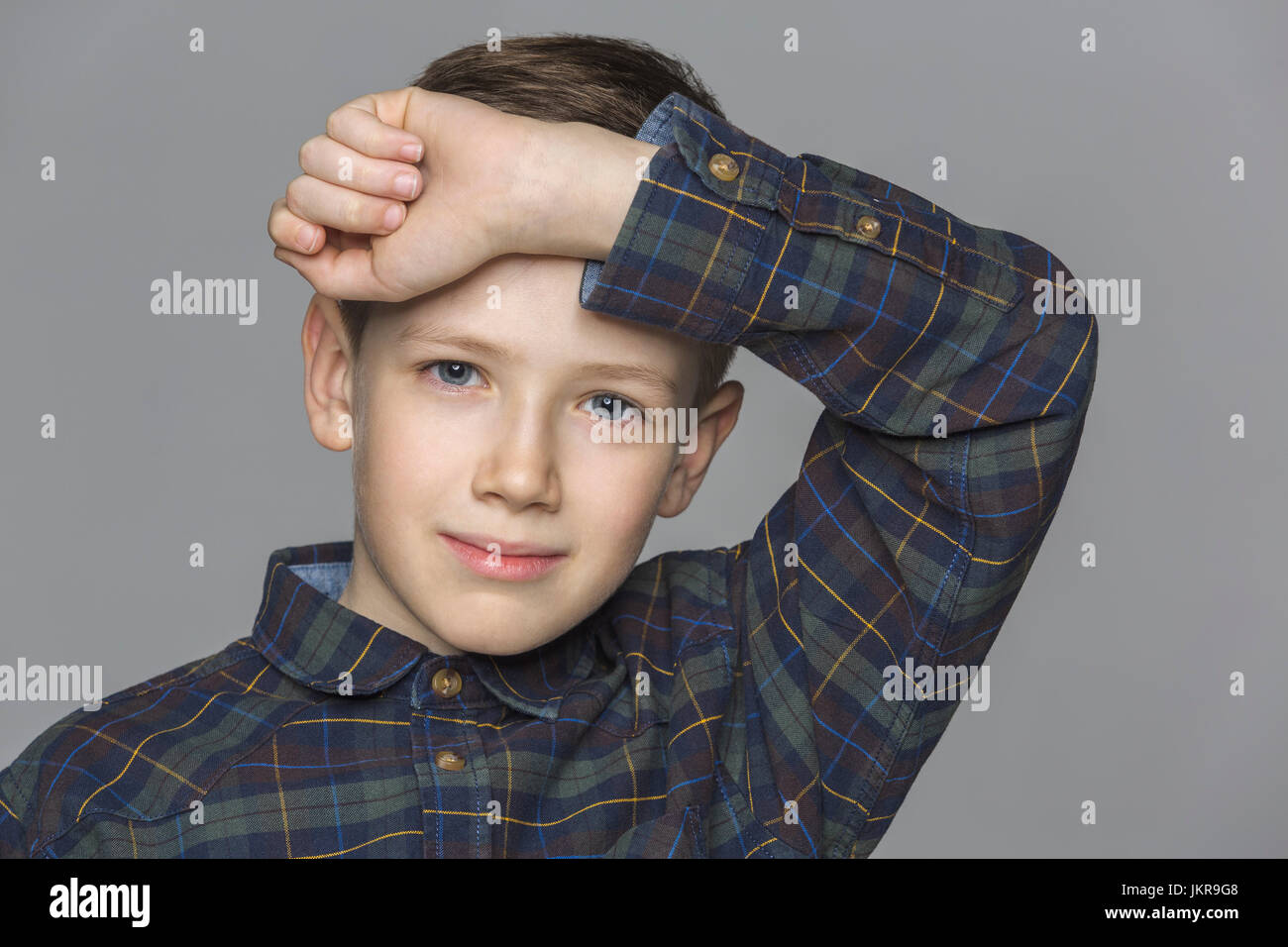 Portrait of boy with arm raised against gray background Stock Photo