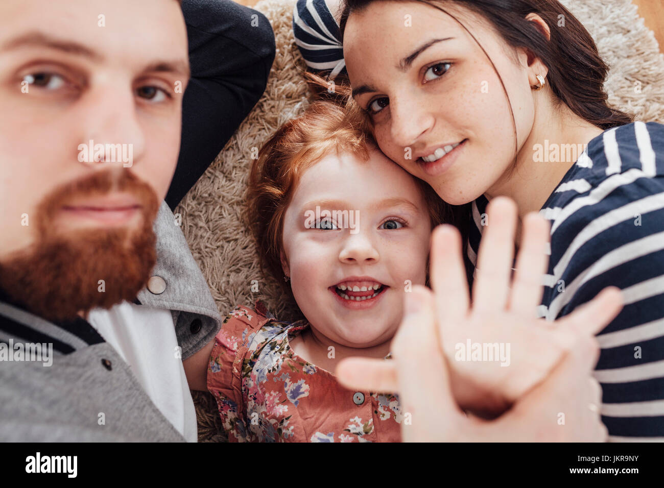 High angle portrait of smiling family lying on carpet at home Stock Photo