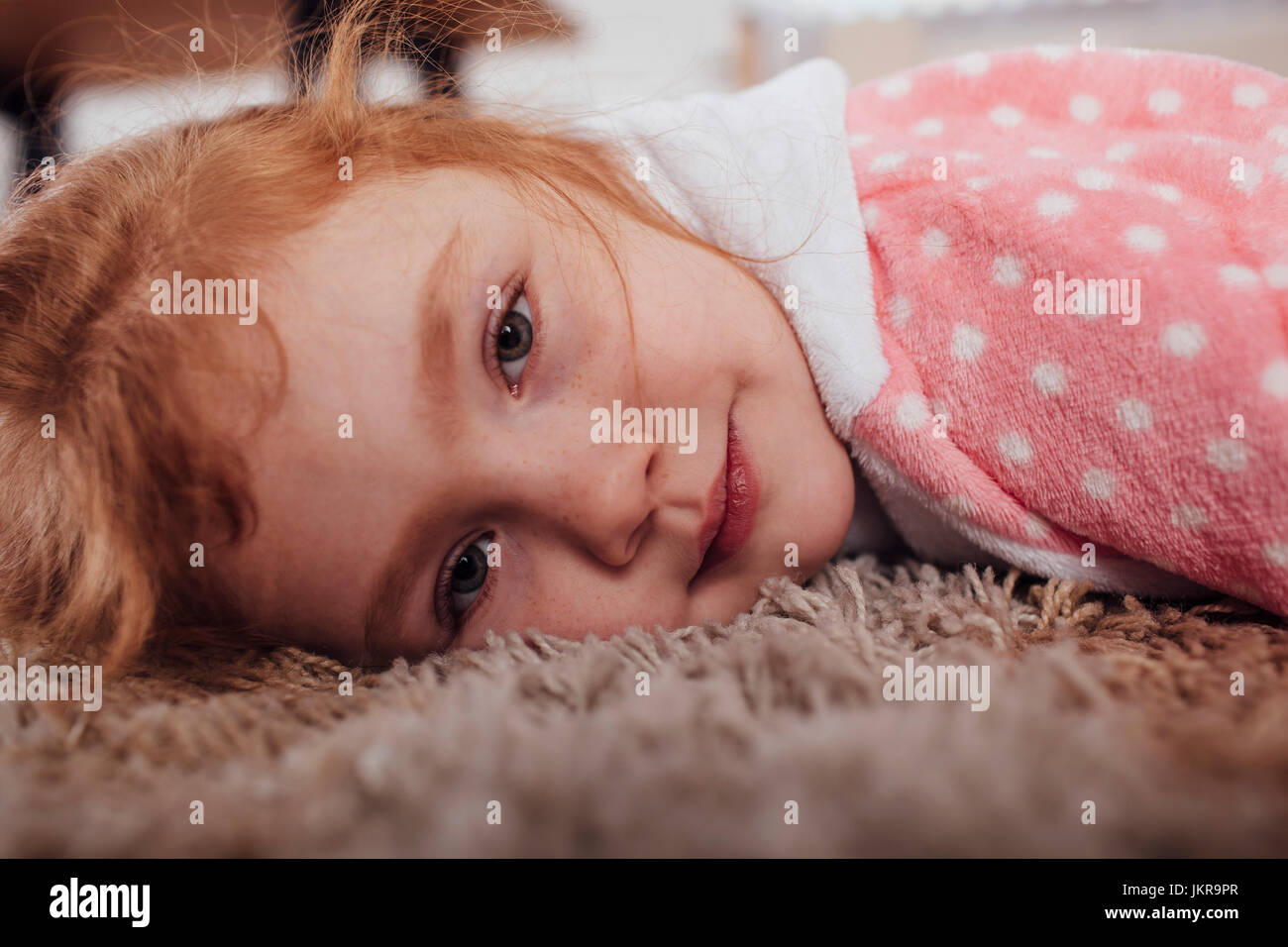 Close-up portrait of girl lying on carpet at home Stock Photo
