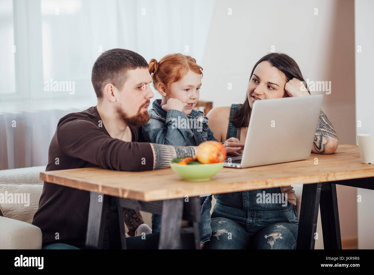 Parents showing laptop to daughter while sitting on sofa at home Stock Photo