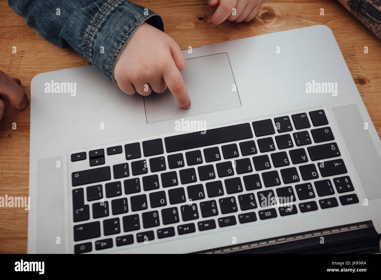 Cropped image of girl scrolling on laptop at wooden table Stock Photo
