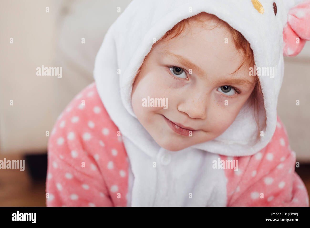 Close-up portrait of smiling girl wearing hooded shirt at home Stock Photo