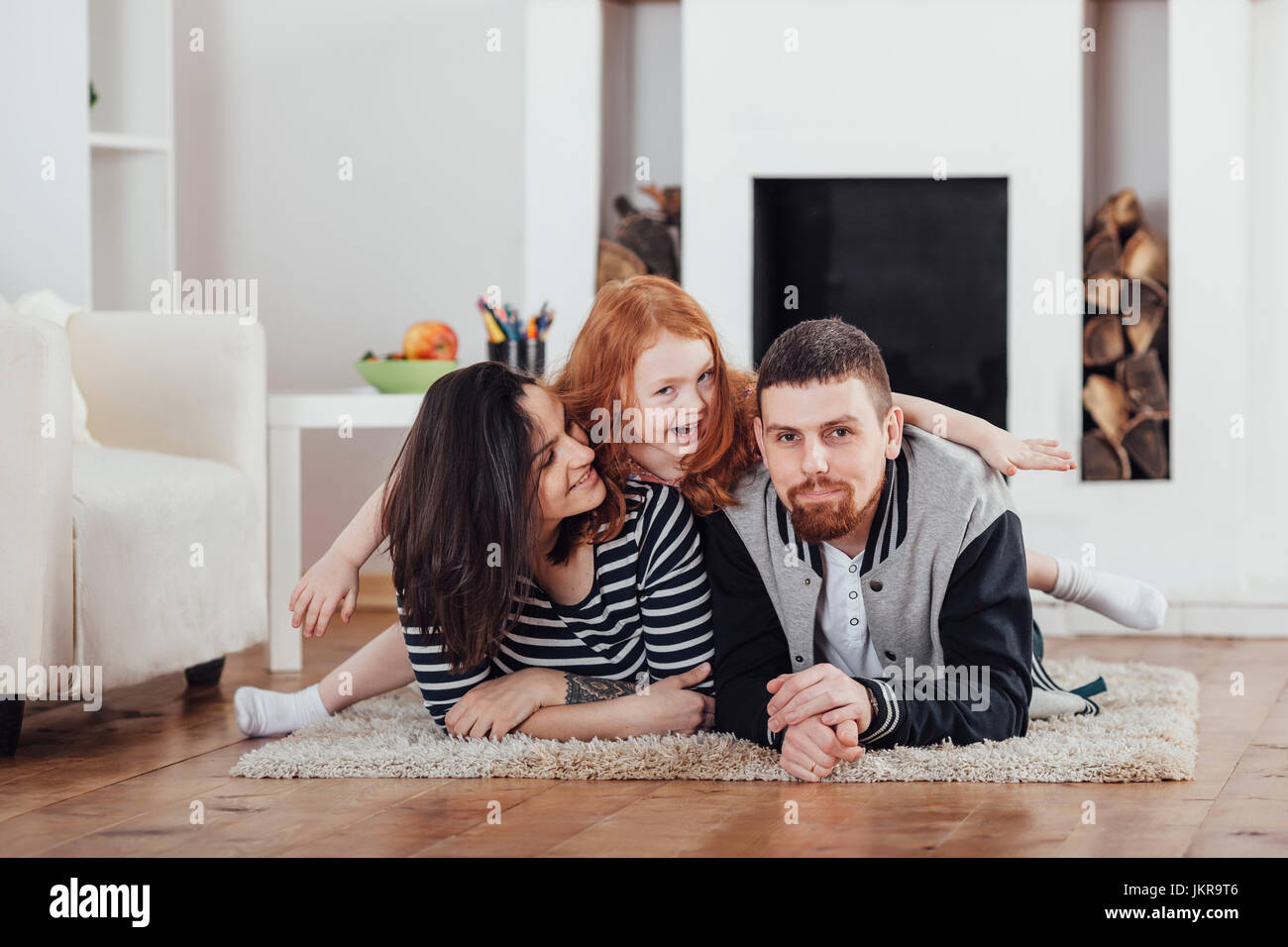 Portrait of cheerful daughter with parents lying on carpet in living room at home Stock Photo