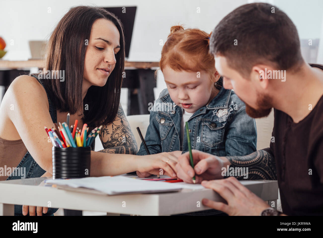 Parents drawing with daughter while sitting in living room at home Stock Photo