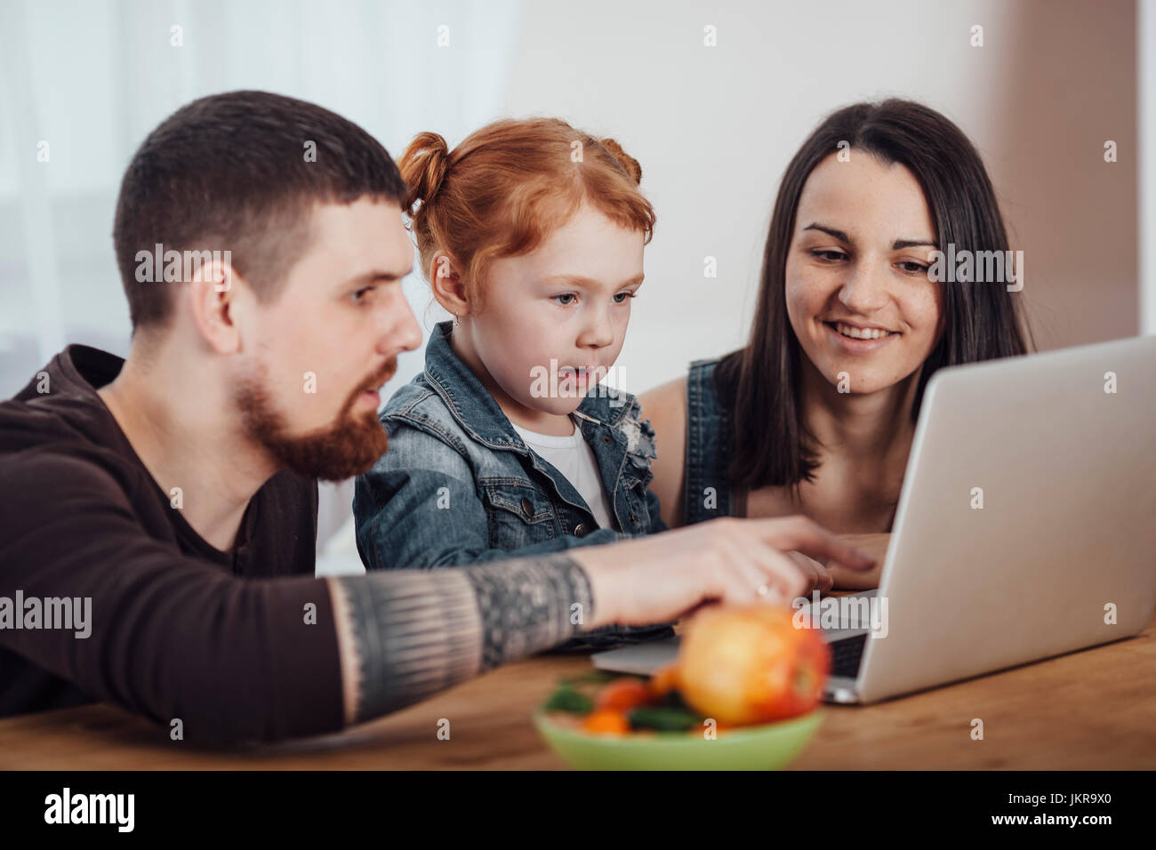 Parents showing laptop to daughter at table in living room Stock Photo