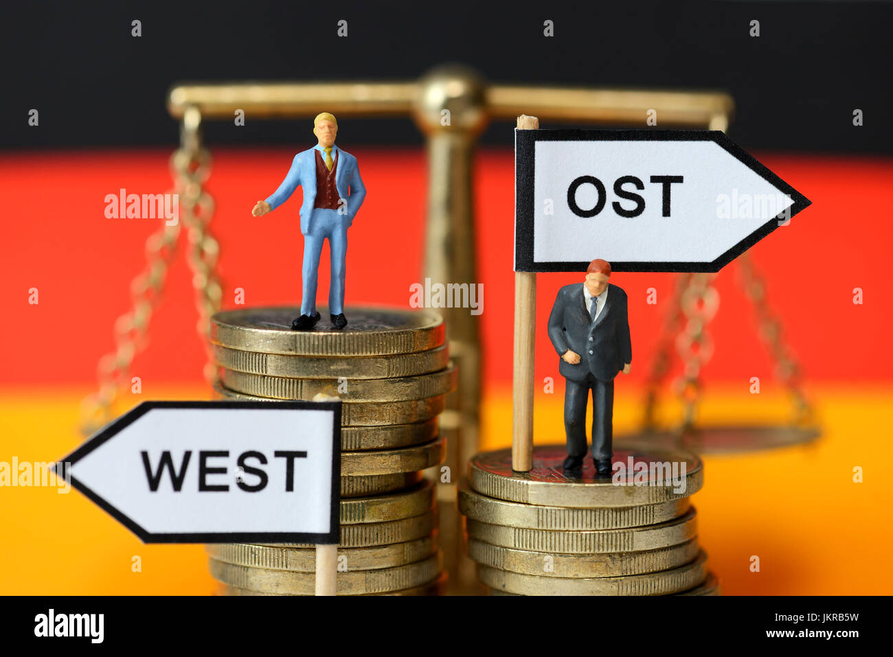 Businessmen-miniature figures on coin piles, unequal salaries in west country and Eastern Germany, Geschäftsmänner-Miniaturfiguren auf Münzstapeln, un Stock Photo