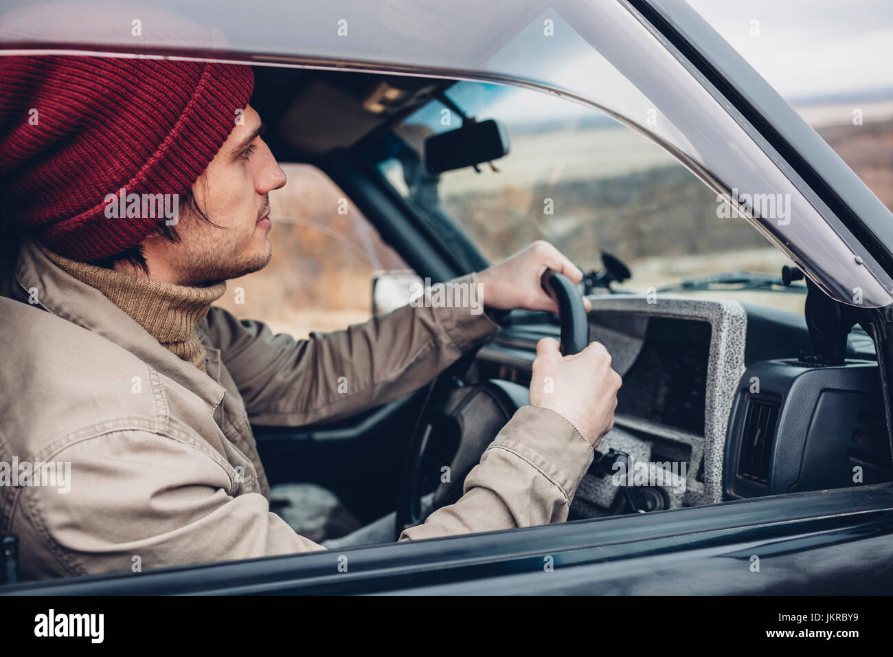 Side view of man wearing knit hat riding sport utility vehicle Stock Photo