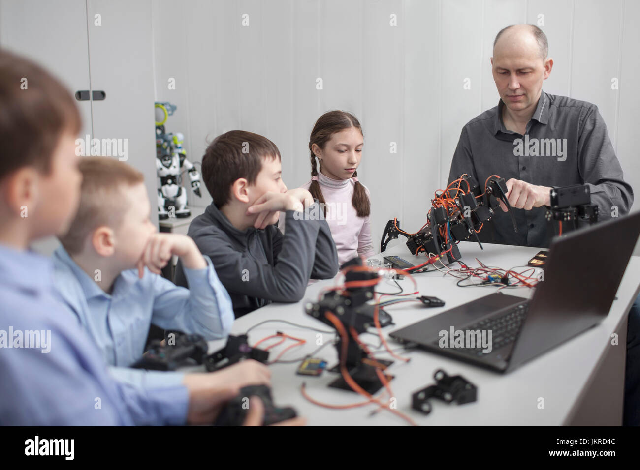 Students looking at teacher operating machinery at table in classroom Stock Photo
