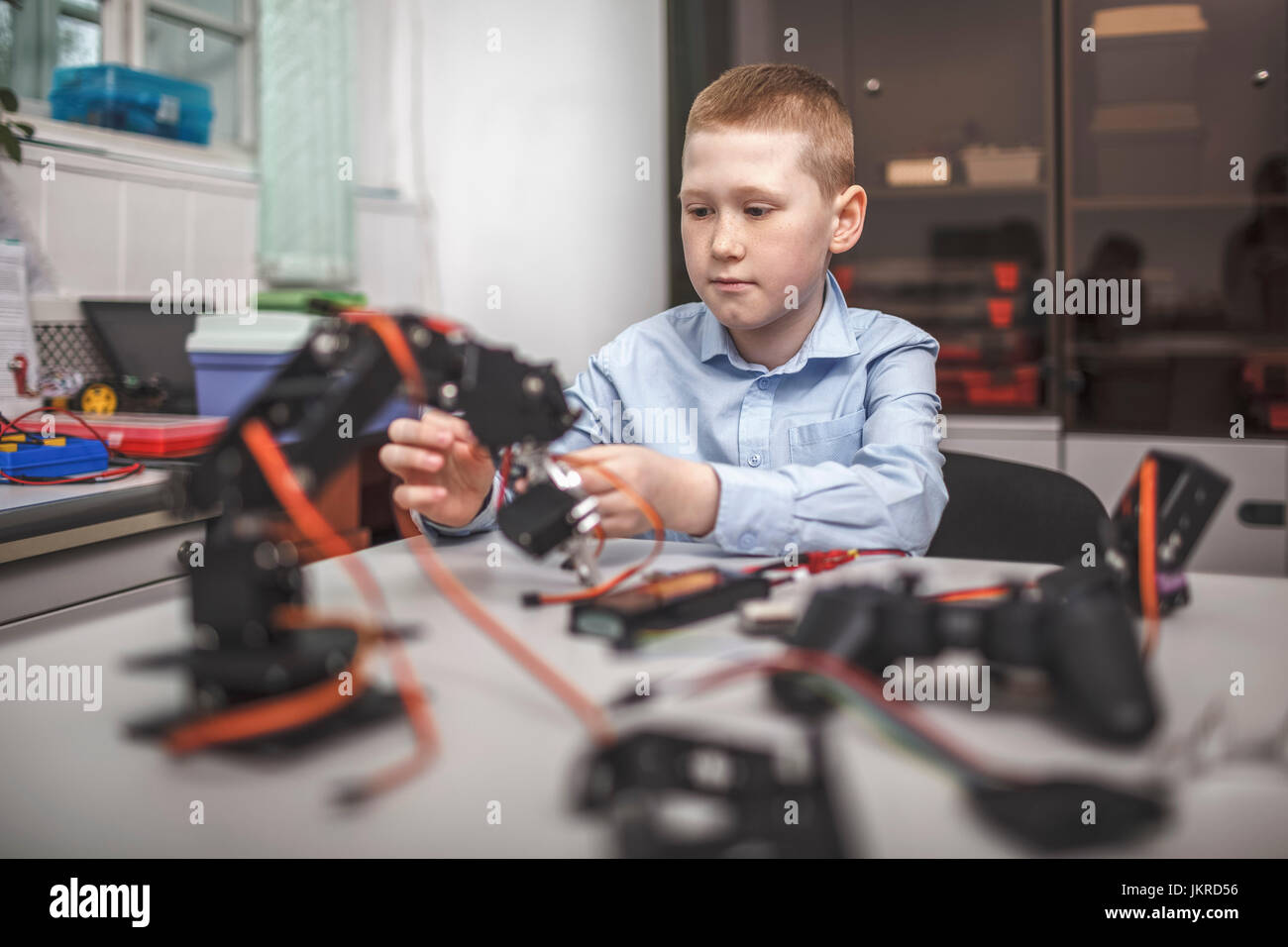 Serious boy operating machinery at table in classroom Stock Photo