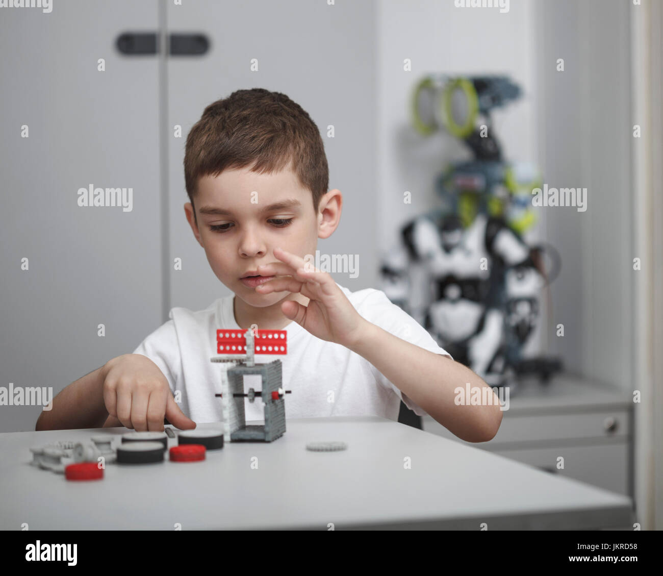 Cute boy operating machinery at table in classroom Stock Photo