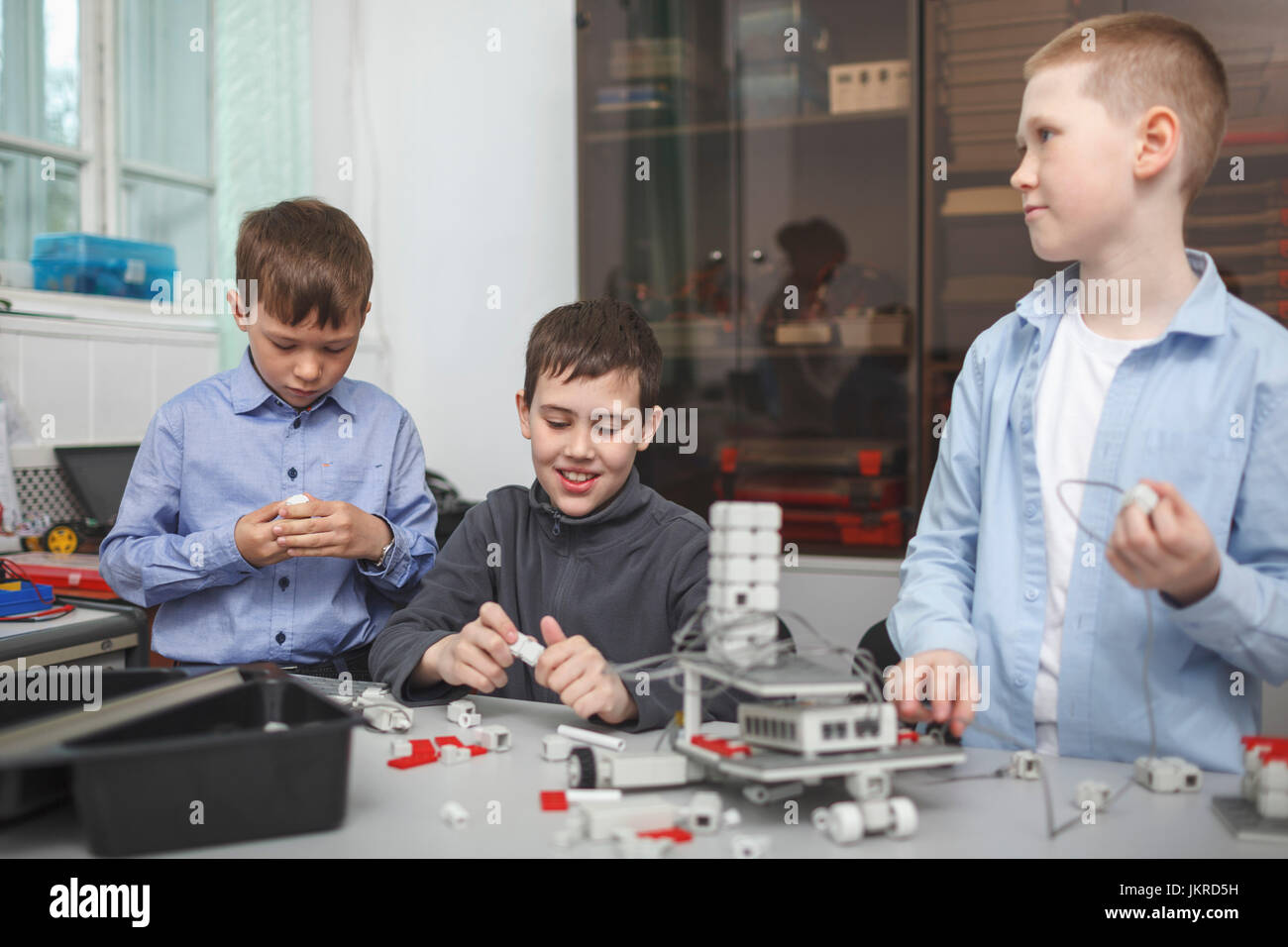 Smiling students working on machine part at table in classroom Stock Photo
