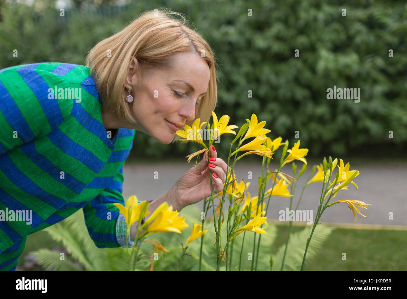 Side view of mature woman smelling yellow flowers at park Stock Photo