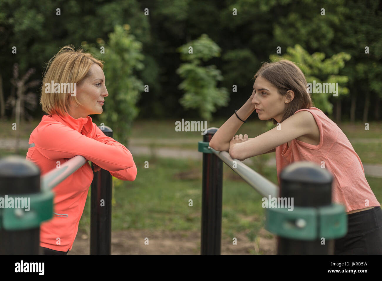 Side view of mother and daughter leaning on railing at park Stock Photo