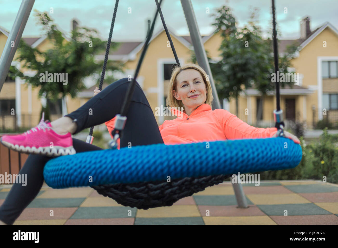 Portrait of smiling woman sitting on swing at park Stock Photo