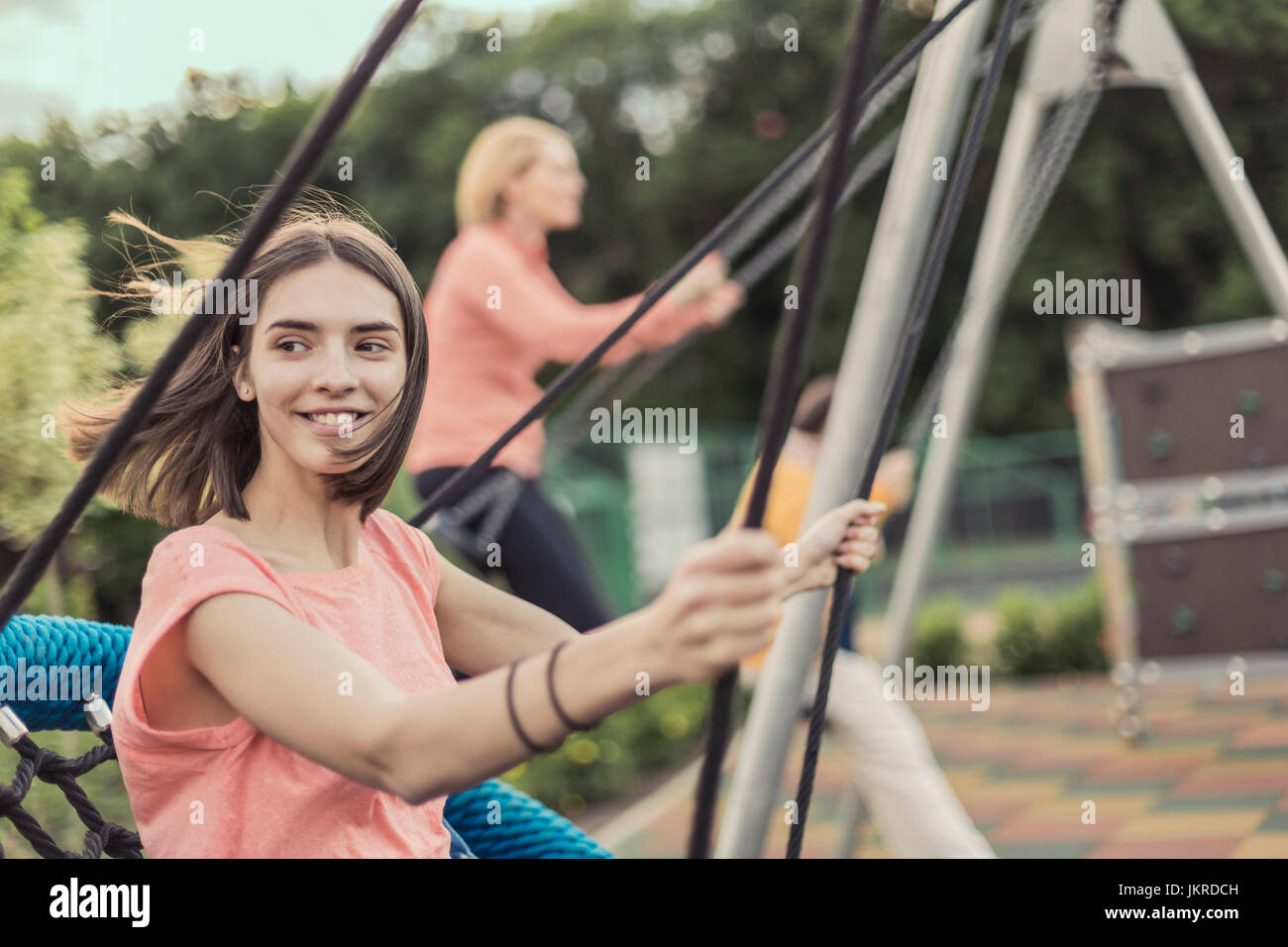 Smiling women swinging on swing at playground Stock Photo