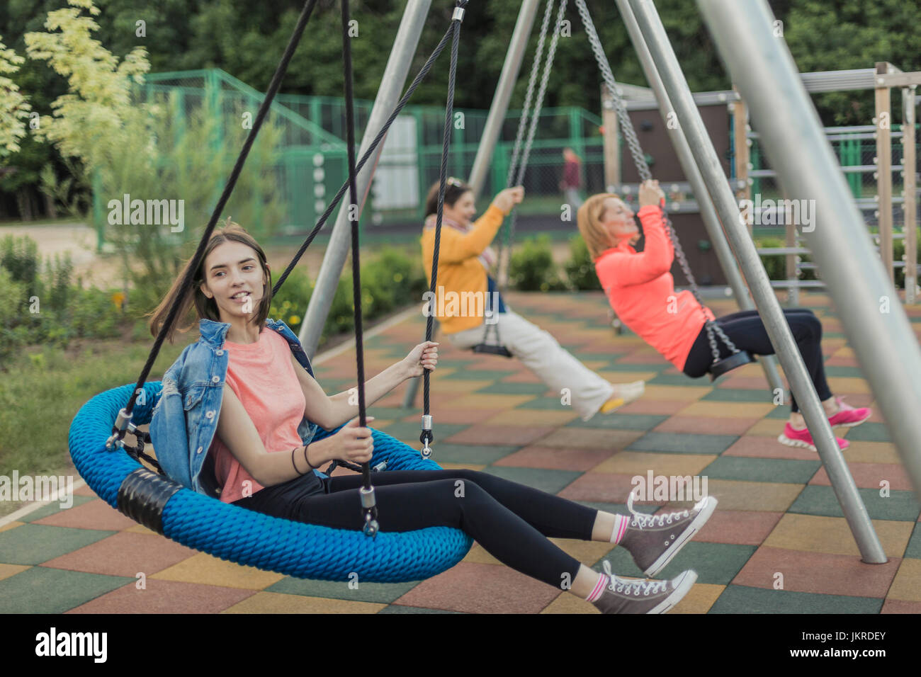 Full length of happy women swinging on swing at playground Stock Photo