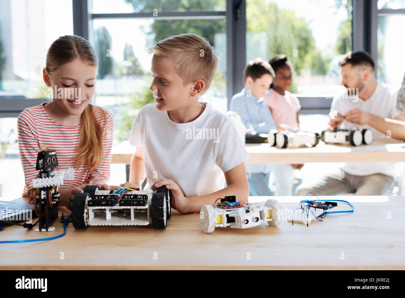 Boy and girl chatting during robotics workshop Stock Photo