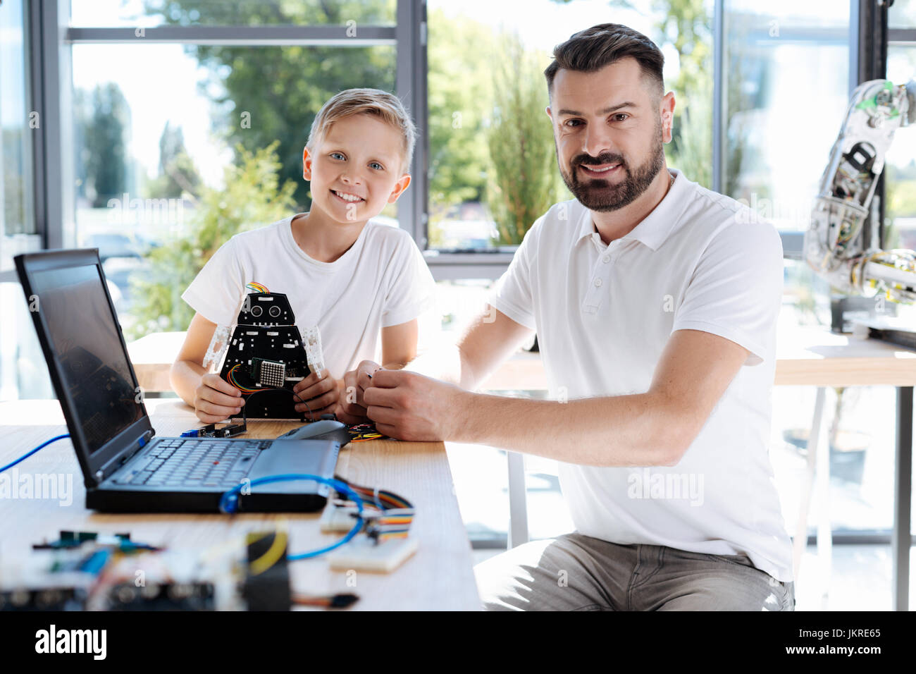 Happy student sitting near his robotics teacher Stock Photo