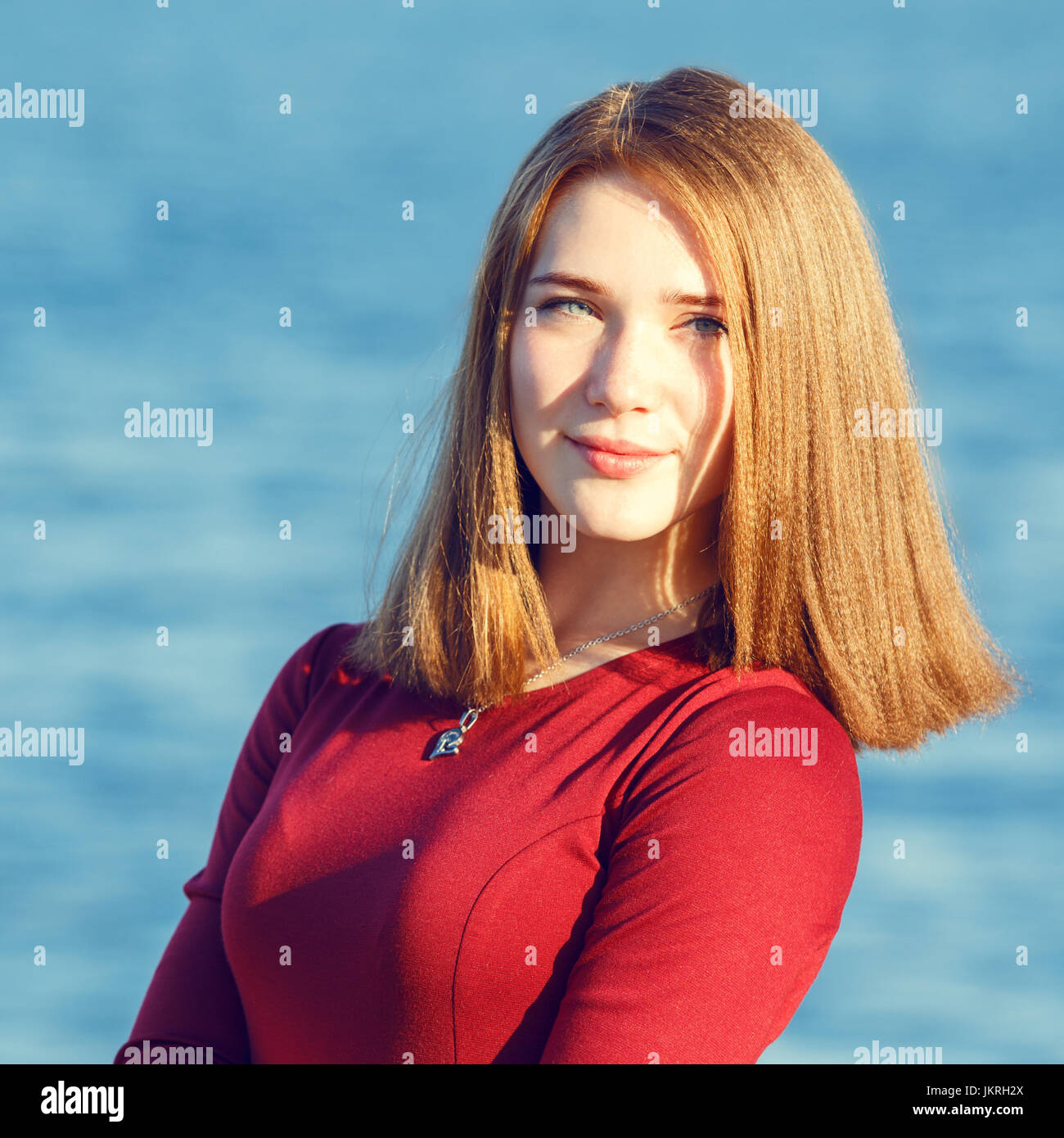Young beautiful woman in red dress standing at seashore Stock Photo - Alamy