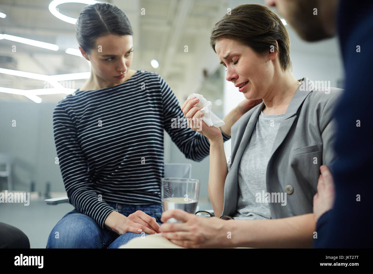 Crying woman telling her problem while compassionate friends listening to her Stock Photo