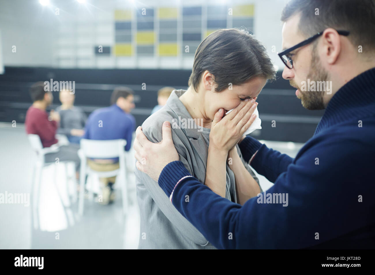 Man embracing crying groupmate and supporting her Stock Photo