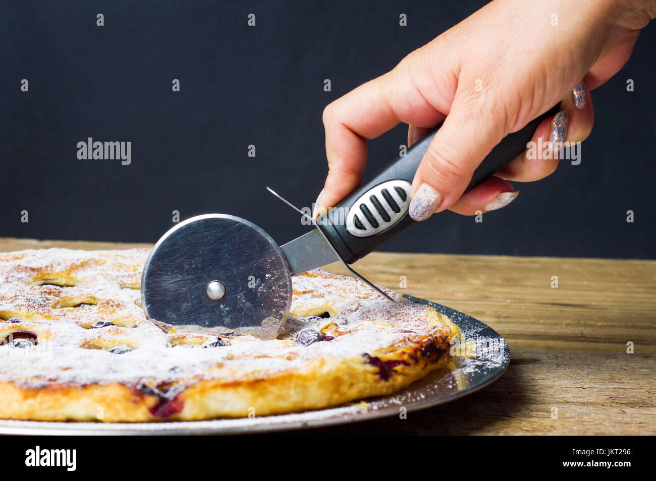 Female cutting sweet pie with a roller cutter knife Stock Photo Alamy