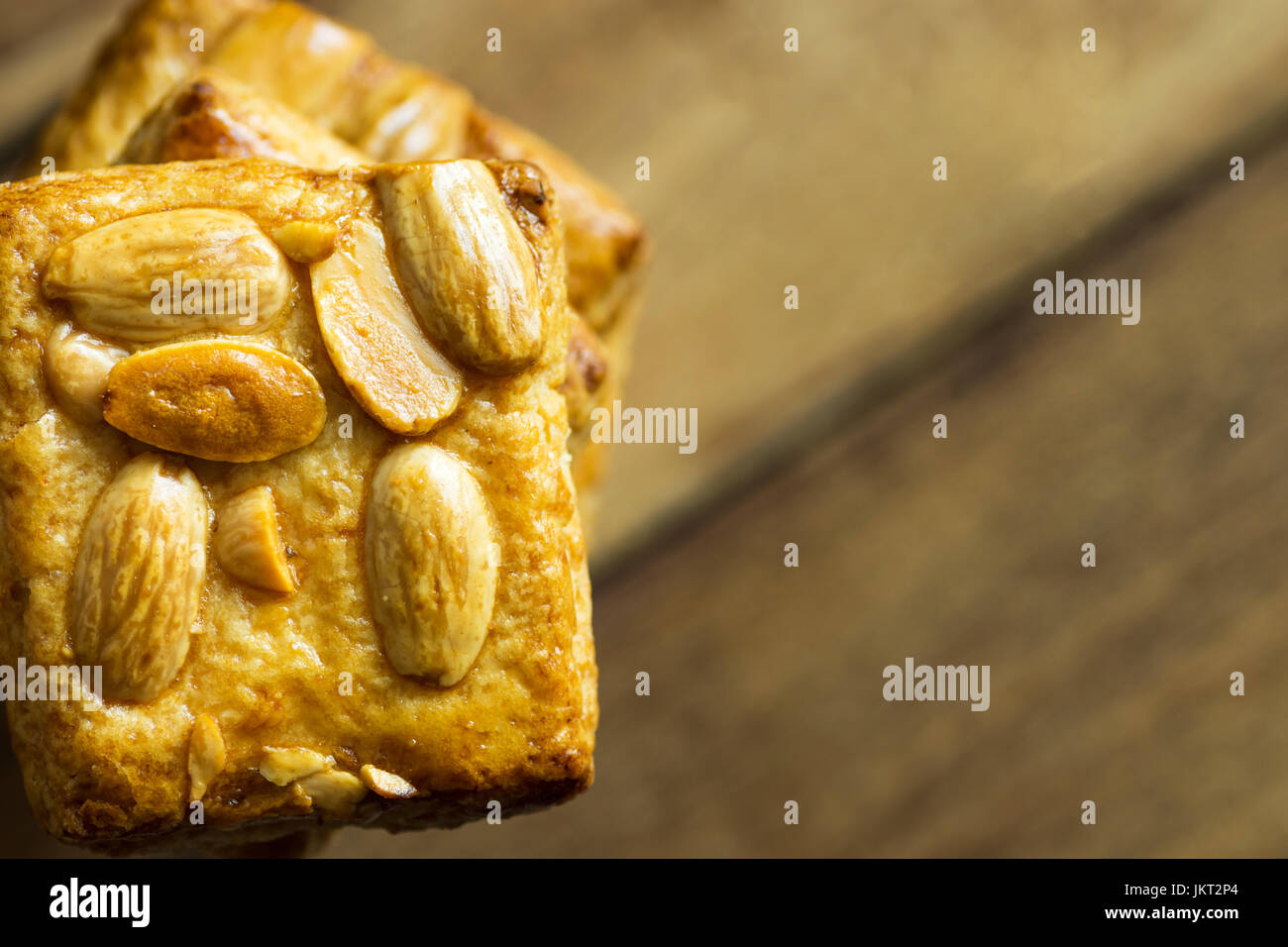 High stack of homemade almond Christmas cookies on plank wood background, top view, copy space, side position, frame, holiday baking, template Stock Photo