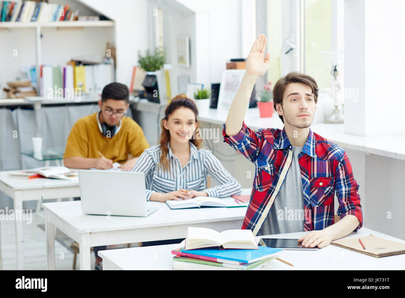 Clever guy raising his hand at lesson Stock Photo - Alamy