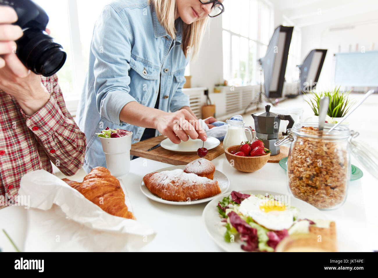 Food stylist preparing table with meals for photographing Stock Photo