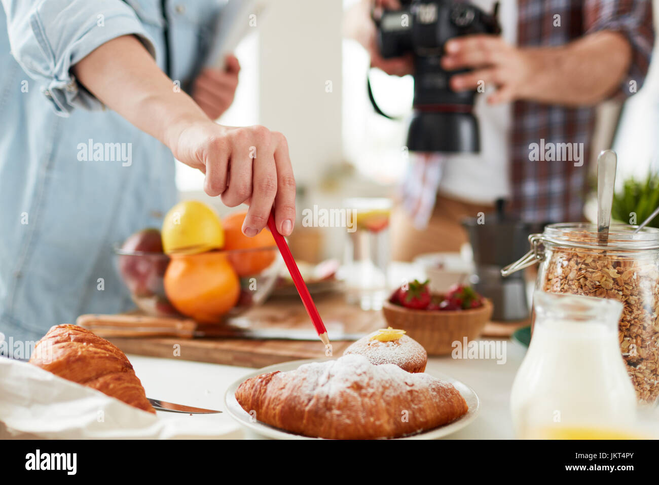 Food-stylist pointing at fresh croissant during working process Stock Photo