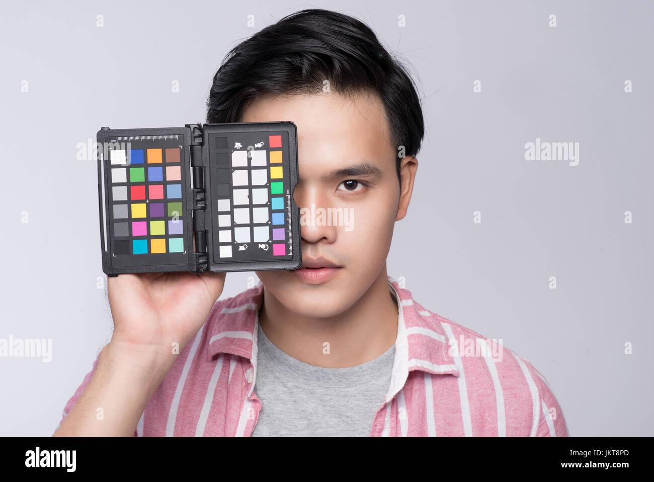 Young asian photographer holding color checker card, while working in studio Stock Photo