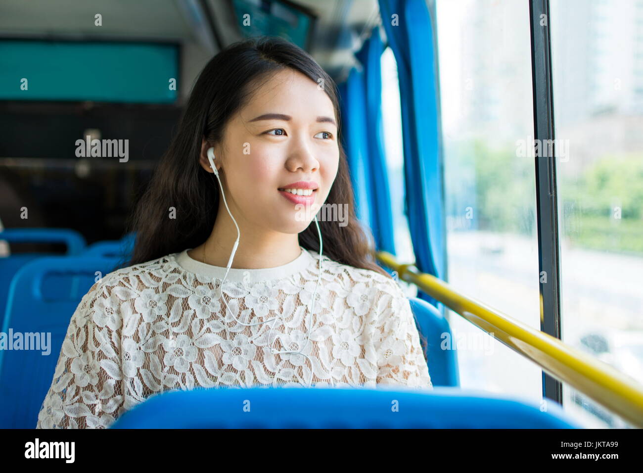 Girl listening to music on a public bus ride Stock Photo
