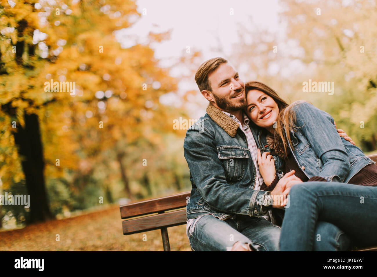 Young loving couple sitting on the bench in the autumn park Stock Photo ...