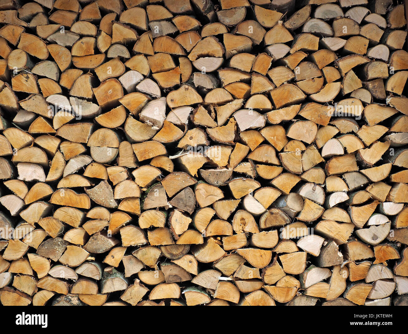 pattern of fully stacked neat woodpile with hewn ends of split logs in Cumbria, England, UK Stock Photo