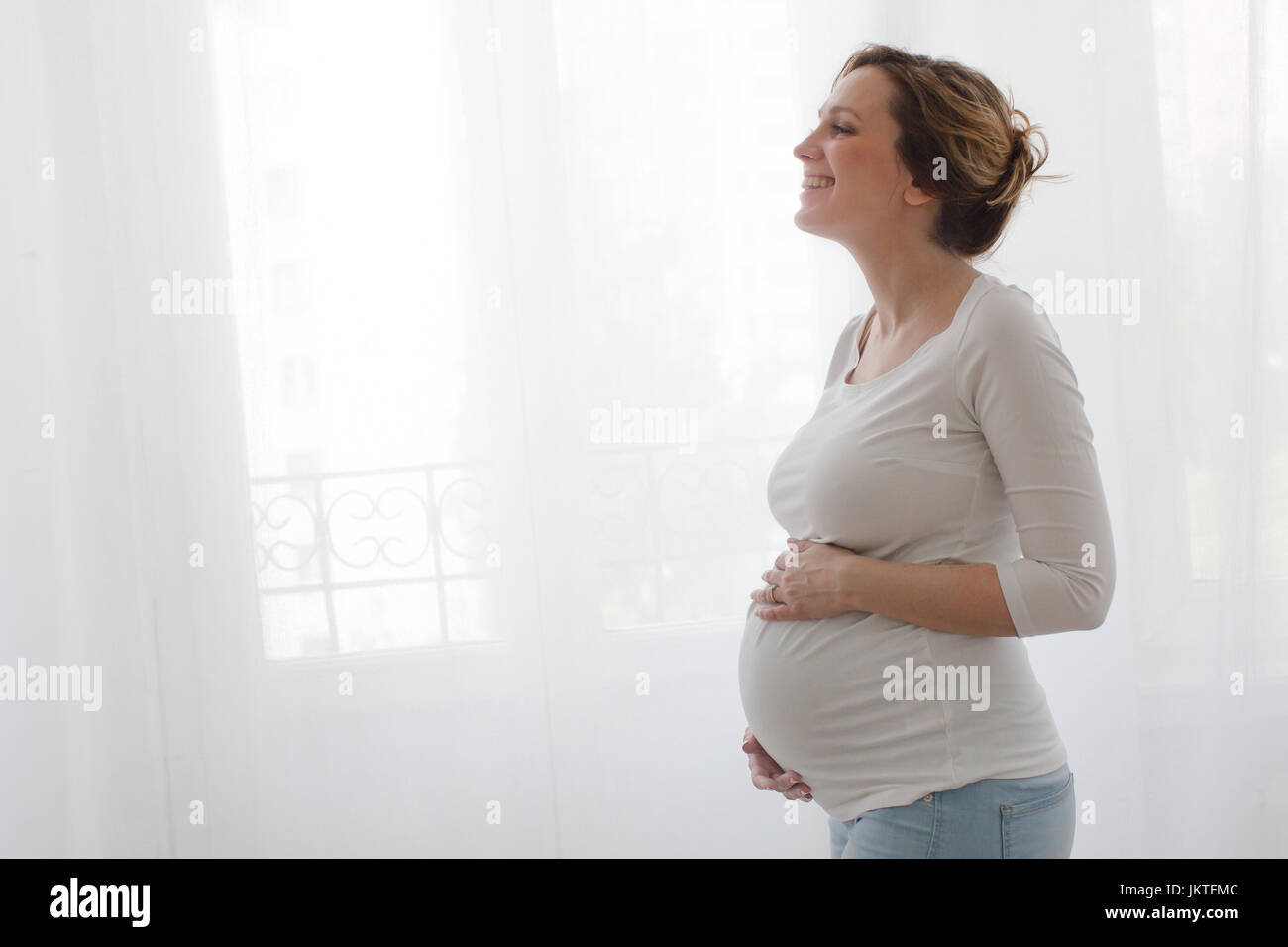 Pregnant happy woman touching belly and laughing Stock Photo - Alamy