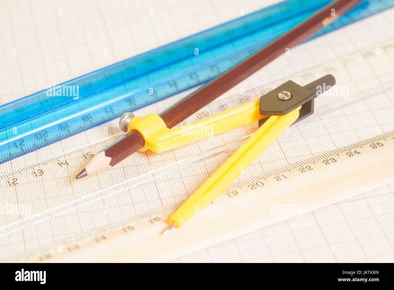 Yellow Drawing compass with pensil and rulers on graph paper ...