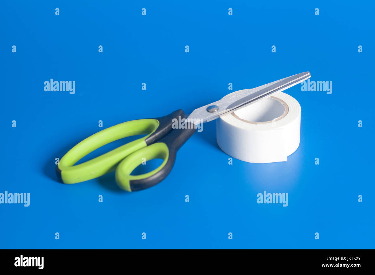 Scissors And Roll Of Duct Tape on blue background Stock Photo