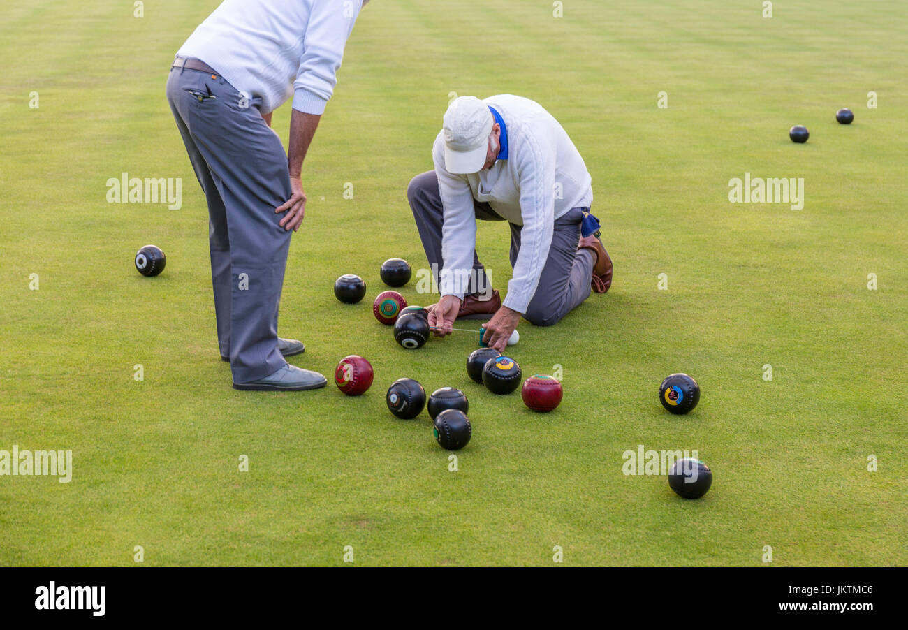 Lawn bowls players using a measure to check the score. Stock Photo
